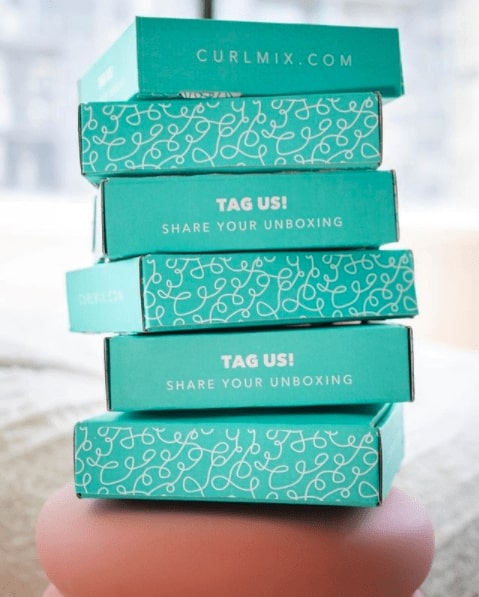 Stack of teal boxes from Curlmix that share the website domain and say _Tag us! Share your unboxing._